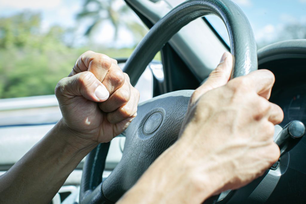 road rage affects drivers - A man behind the steering wheel angry at other drivers banging on his horn in anger.