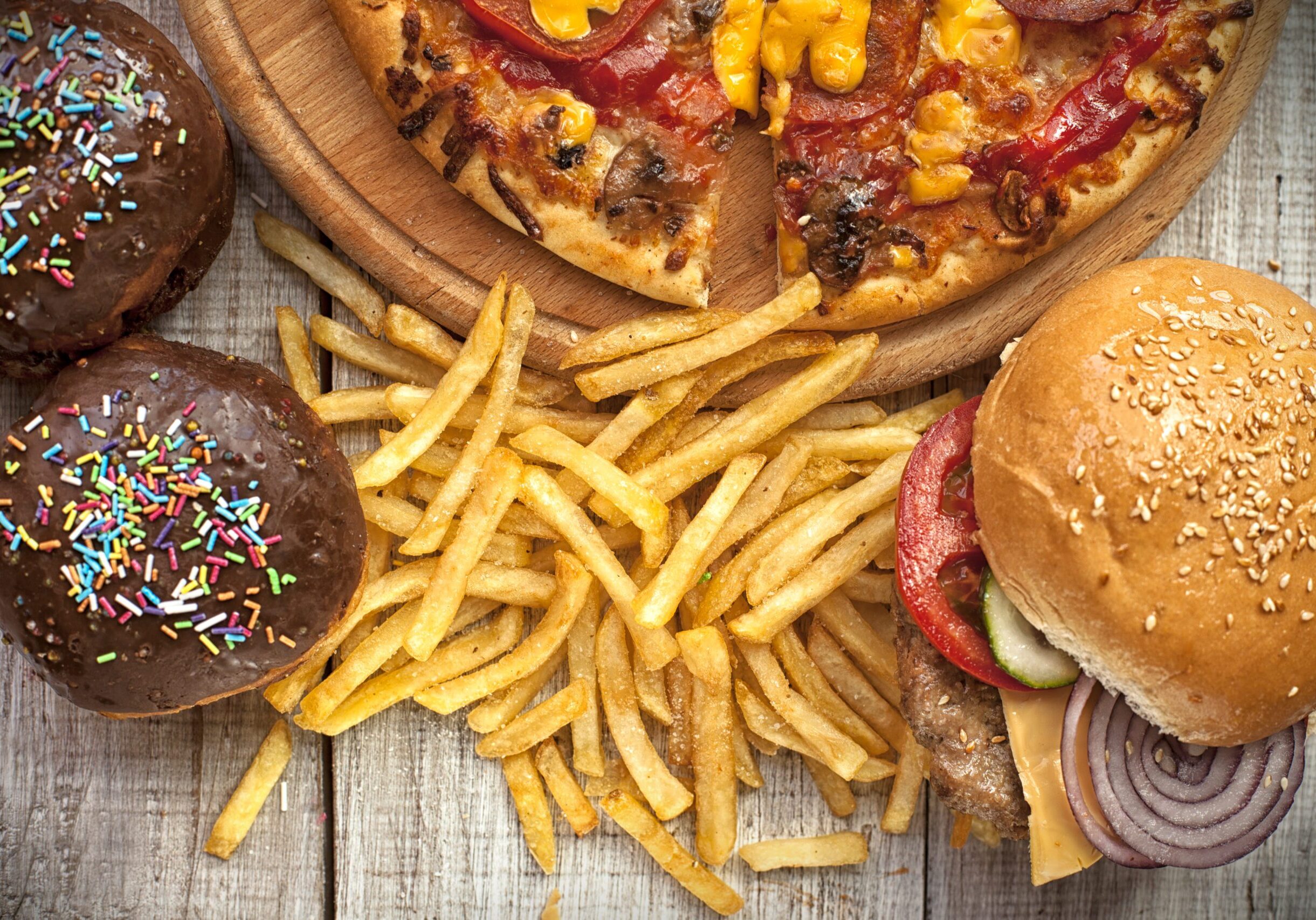 Closeup of home made burgers , french fries and donuts on wooden background